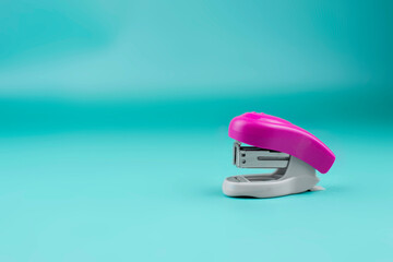 gray-pink stapler on a blue background. Bright stationery