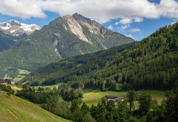 Obraz premium A village in the Alps among forests, against the backdrop of mountain peaks.