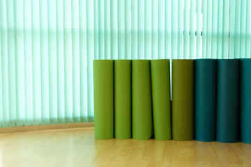 Yoga mats on wood floor of yoga classroom with green curtain.