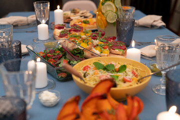 Part of served festive table with vegetable salad, homemade sandwiches and pasta