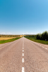 Country asphalt road through agricultural fields on a sunny day. Logistics and transport background
