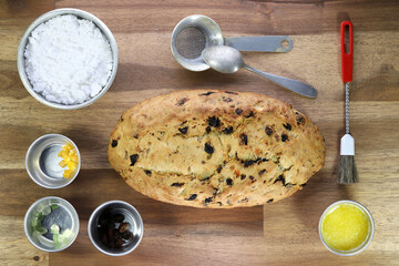 freshly baked traditional Saxon Christmas Stollen with some baking ingredients on wooden background