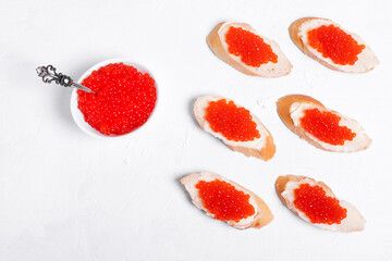 Sandwiches with red caviar and butter on baguette on the white wooden table. Top view