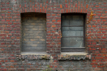 Old rough dirty brick wall facade with vintage detail of rectangular windows frame filled with brick.