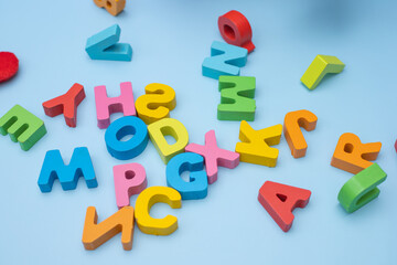 Fototapeta premium Set of coloured wooden letters on blue background. Top view.