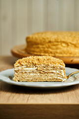 Slice of Honey cake on plate. Board with delicious tasty homemade cake on table. Wooden background.