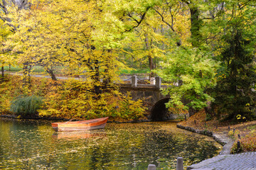 Ancient stone bridge in the autumn National Dendrology Park of Sofiyivka, Uman, Ukraine. Pleasure boat on the water.