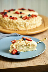 Slice of napoleon cake on plate. Board with delicious tasty homemade cake on table. Wooden background.