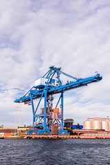 Fototapeta na wymiar Massive blue crane unload cargo in a seaport in Sweden