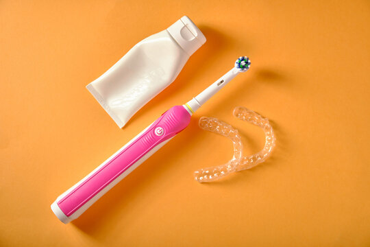 Electric toothbrushes, toothpaste, plastic mouthguards, on an orange background, top view