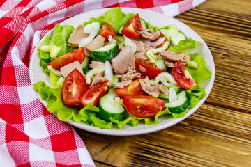 Tasty tuna salad with lettuce and fresh vegetables on wooden table