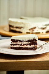 Slice of three chocolate cake on plate. Board with delicious tasty homemade cake on table. Wooden background.