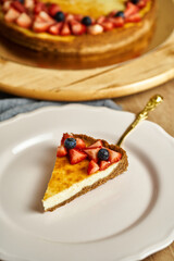 Slice of cheesecake on plate. Board with delicious tasty homemade cake on table. Wooden background.