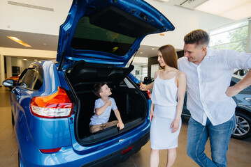 A little boy sits in the trunk while his parents choose a new car