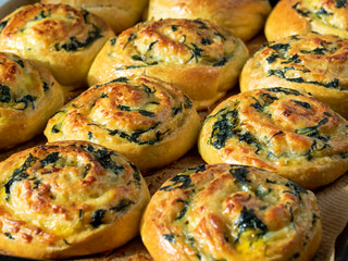 dough curls with spinach and cheese on a baking sheet. Side view