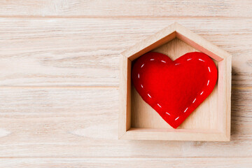 Top view of red textile heart in a house on wooden background. Home sweet home concept. Valentine's day