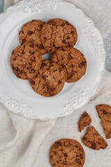 Freshly baked homemade crunchy cookies with chocolate chips, peanut butter or salted caramel. A delicious treat for gourmets. Biscuits in a white plate. Selective focus, top view