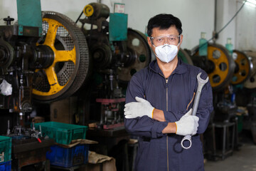 portrait engineer worker or mechanic wearing helmet and face mask with holding wrench