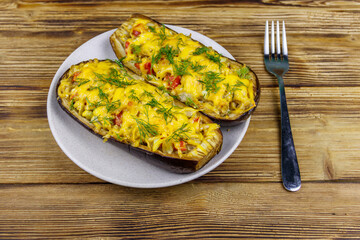Baked stuffed eggplants on a wooden table. Healthy food and dieting concept