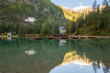 Fototapeta na wymiar A view of the lake Pragser Wildsee in the Dolomites with a chain of boats, mountains and woods in autumn in South Tyrol, Italy.