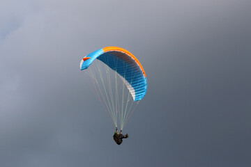 Paraglider flying wing in a cloudy sky	