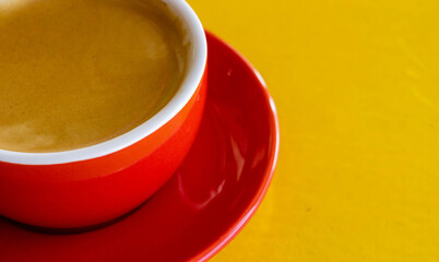 A photo of a red coffee mug on a yellow table