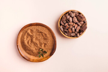 Flatlay Cocoa beans, cocoa powder on a pink background. The concept of healthy eating.