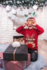 Little cute little girl in Christmas clothes is happy New Year gifts by making round glasses of bagels