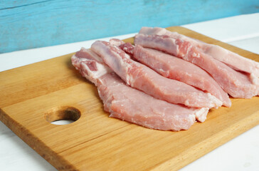 chopped pieces of pork loin on a cutting board, fatty meat