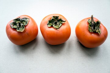 Three persimmons placed in a row