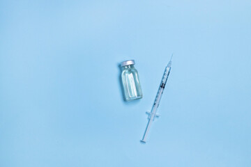 Coronavirus, flu or measles vaccine vial with syringe on blue background, horizontal banner with copy space