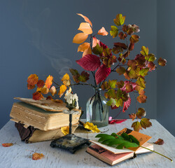 Still life with autumn leaves, extinguished candles and books. Vintage.