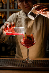 man accurate add ingredients to glass with small pumpkin and pepper inside