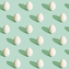 Seamless pattern from white eggs on light green paper. Food concept. Easter print.