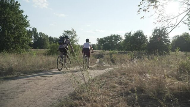 Active couple biking on scenic road. Sport couple riding mountain bicycles in countryside. Healthy Lifestyle Concept. Fitness, sport, people and bike. Happy man and woman exercising with cycle outdoor