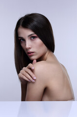 Portrait of a beautiful girl with bare shoulders on a light background