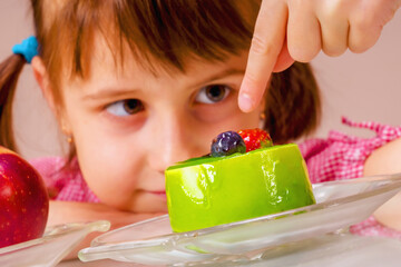 Close up beautiful young girl eating cake, she prefer sweets than healthy food and fruit. Healthy and rubbish food concept.  Horizontal image.