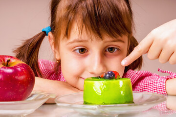 Beautiful young girl eating cake, she prefer sweets than healthy food and fruit. Healthy and rubbish food concept.