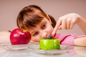 Beautiful girl eating cake, she prefer sweets than healthy food and fruit. Selective focus on green cake and finger.