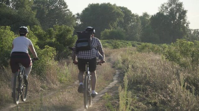 Happy couple on a bike ride in the countryside. Fitness, sport, people and healthy lifestyle concept. Holiday biking in coutryside. Active pair cyclists ride mountain bikes on scenic road