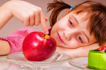 Close up portrait of beauiful young girl looking a red apple and green cake. She prefer fruit and vegetable Health, diet, lifestyle concept. Horizontal image.