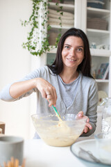 Young woman in white clothes kneading a pie of white flour on a white background. Soft focus