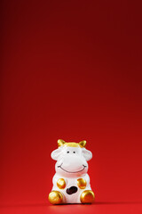 Figurine of a cow from on a red background, free space for text.