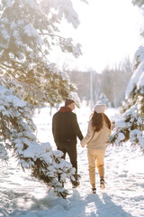 Fototapeta na wymiar Young couple on winter holiday in a snowy forest. Happy man and woman having fun and laughing outdoors in winter. People, season, travel, love and leisure concept.