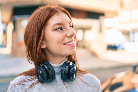 Young irish teenager girl smiling happy using headphones at the city.