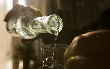 Palinka, the famous homemade Hungarian alcohol pouring from a bottle to glass. Stock photo from...