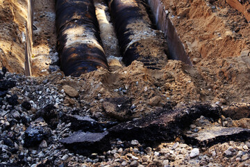 Rusty pipes of the city highway. Dug trench and broken asphalt. Scheduled pipeline repair. Close-up