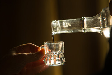 Palinka, the famous homemade Hungarian alcohol pouring from a bottle to glass. Stock photo from...