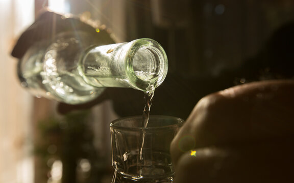 Palinka, the famous homemade Hungarian alcohol pouring from a bottle to glass. Stock photo from Hungary. 