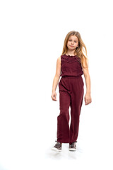 Young blonde girl wearing a burgundy jumpsuit walks, isolated